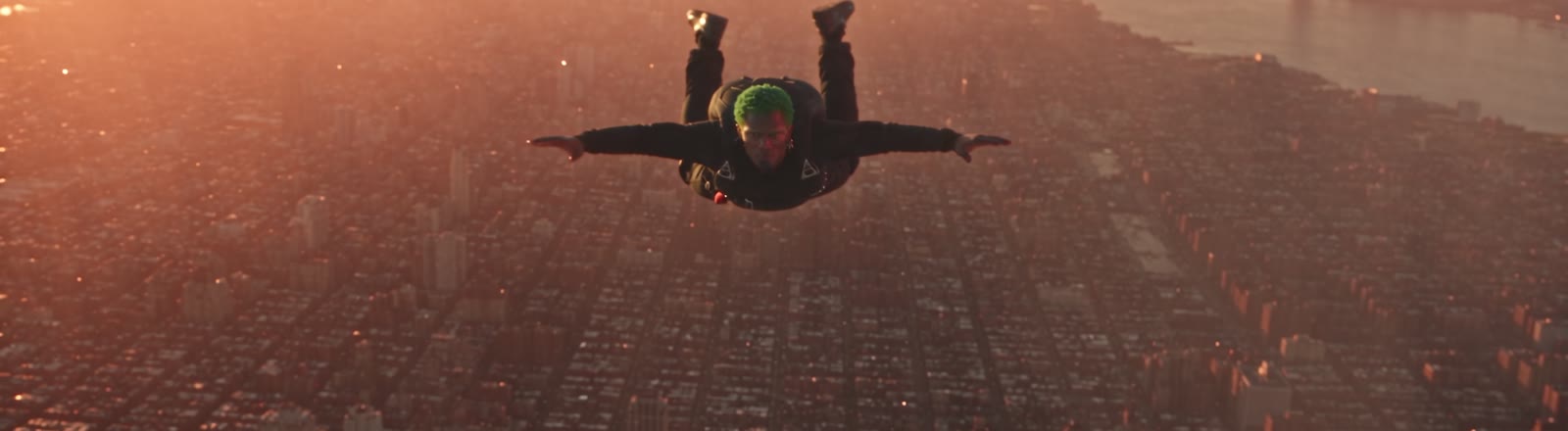 Plan tiré du film d'essai Chute libre, généré par IA : un homme en chute libre au-dessus d'une ville au coucher du soleil