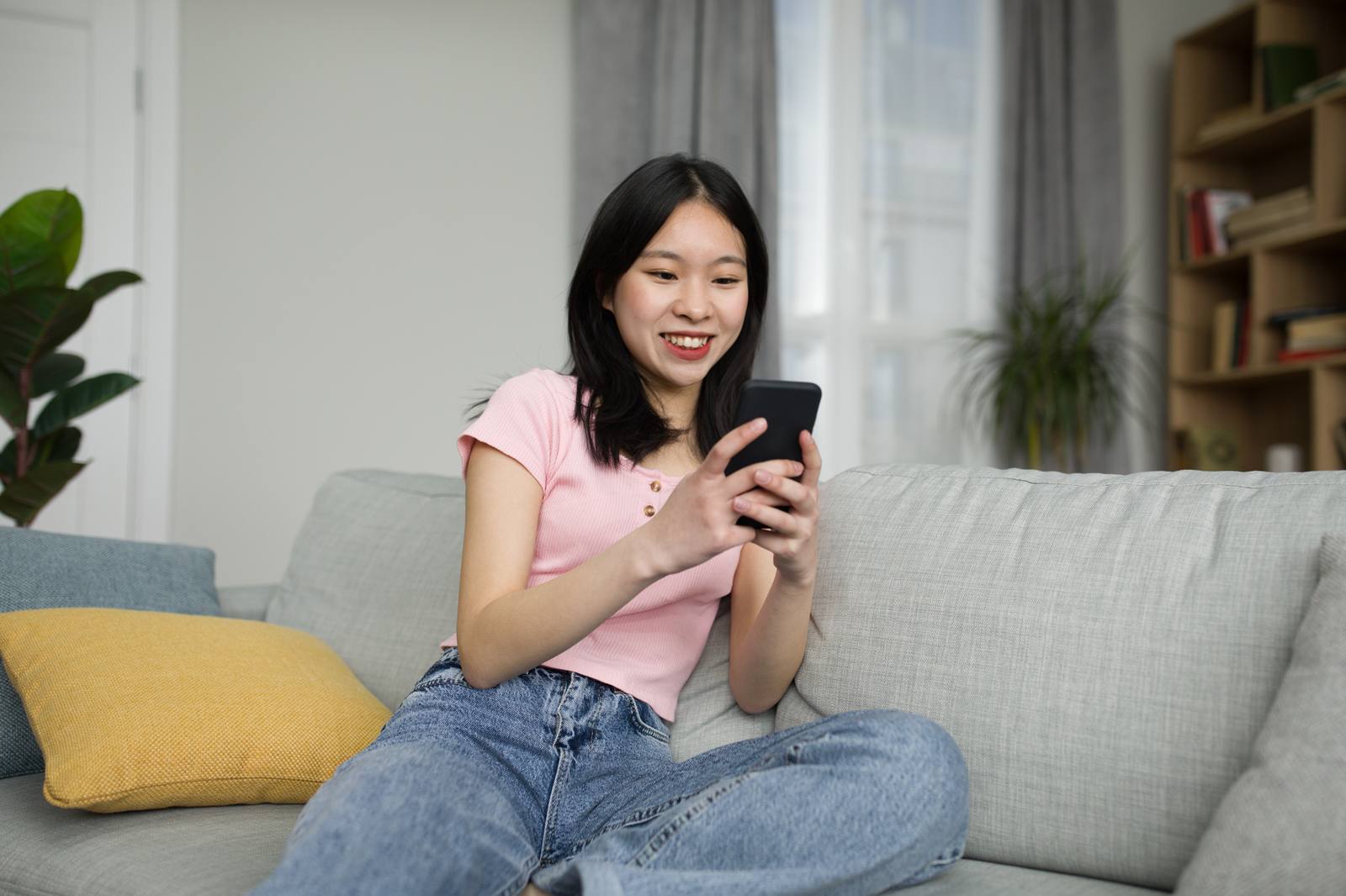 Créatrice souriante qui consulte sa communauté sur son téléphone dans son salon