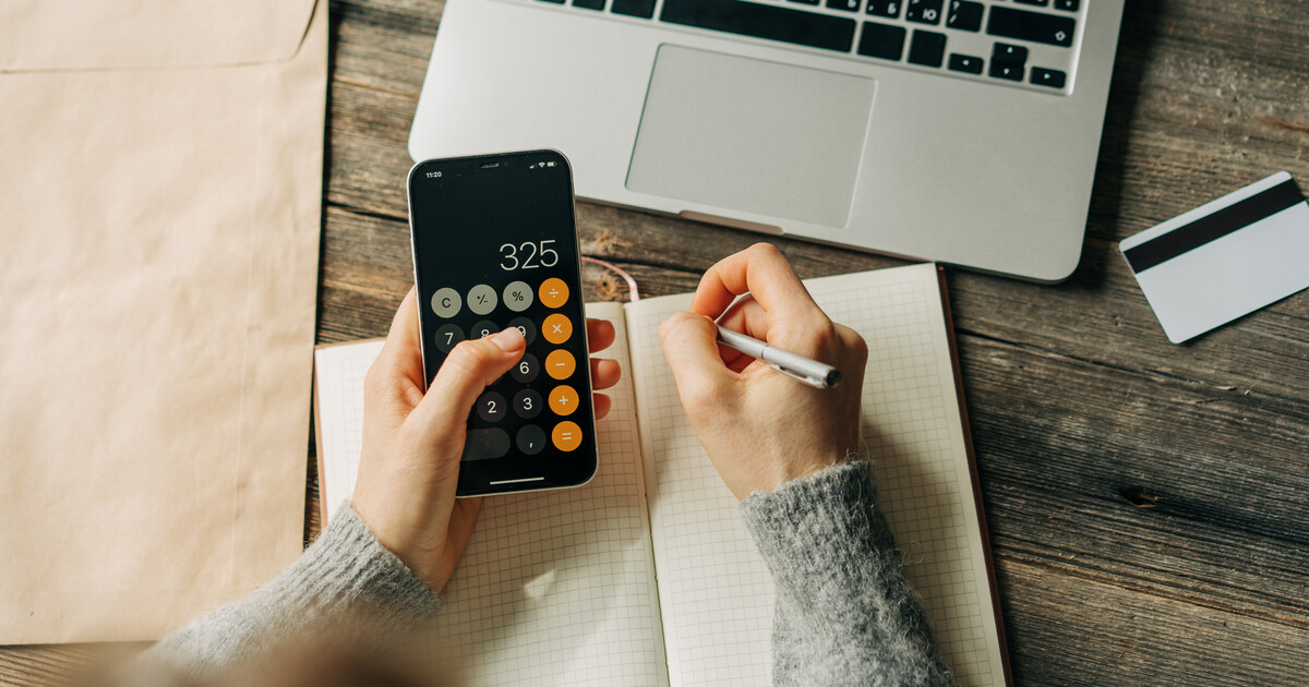 Vue de dessus : quelqu un calcule son budget d achat sur une calculatrice, carnet et ordinateur portable