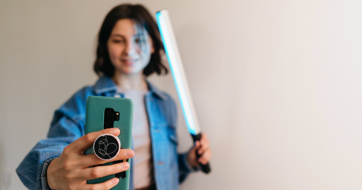 Jeune créatrice filmant une vidéo au téléphone avec un stick lumineux