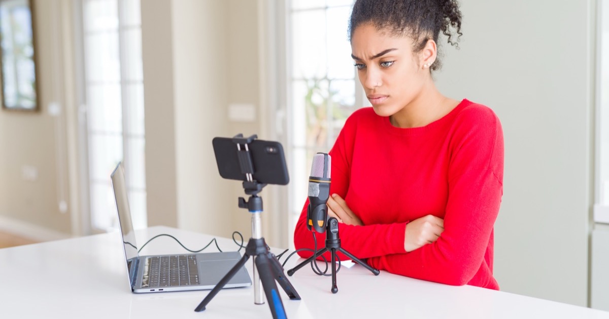 Créatrice sceptique devant son setup de live : téléphone, micro et ordinateur portable