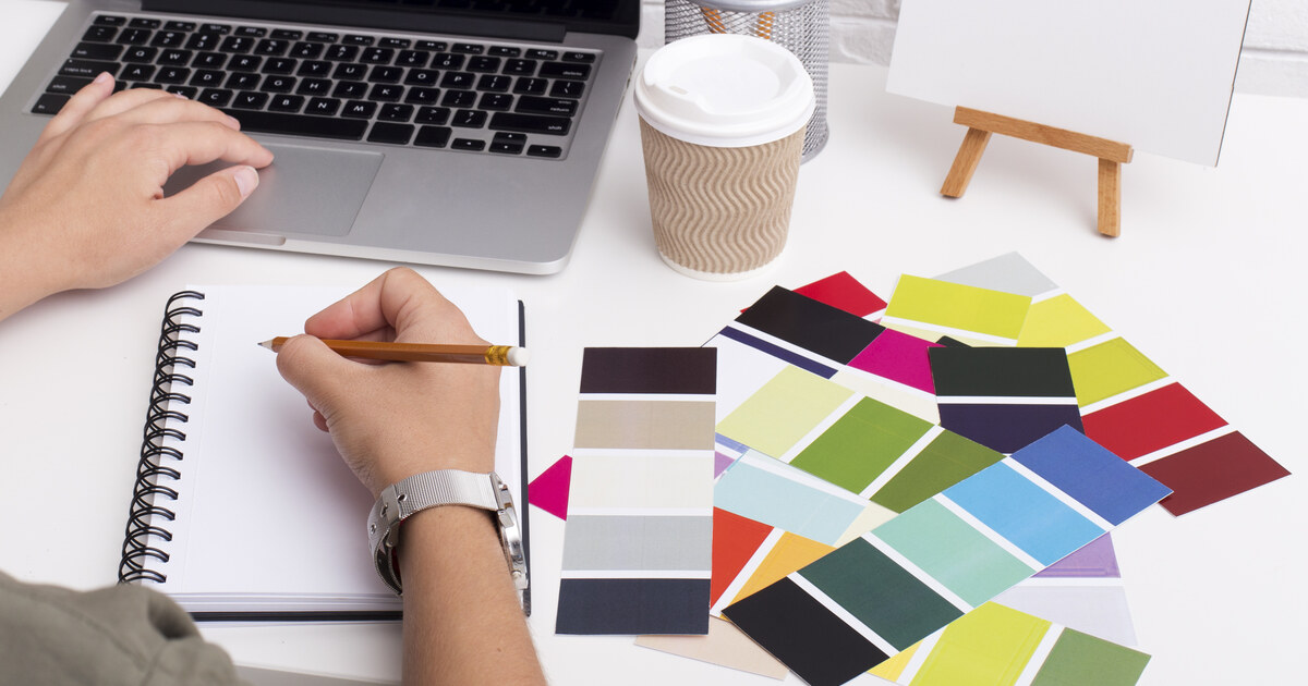 Designer qui compose une identité visuelle : nuancier de couleurs, carnet et ordinateur portable