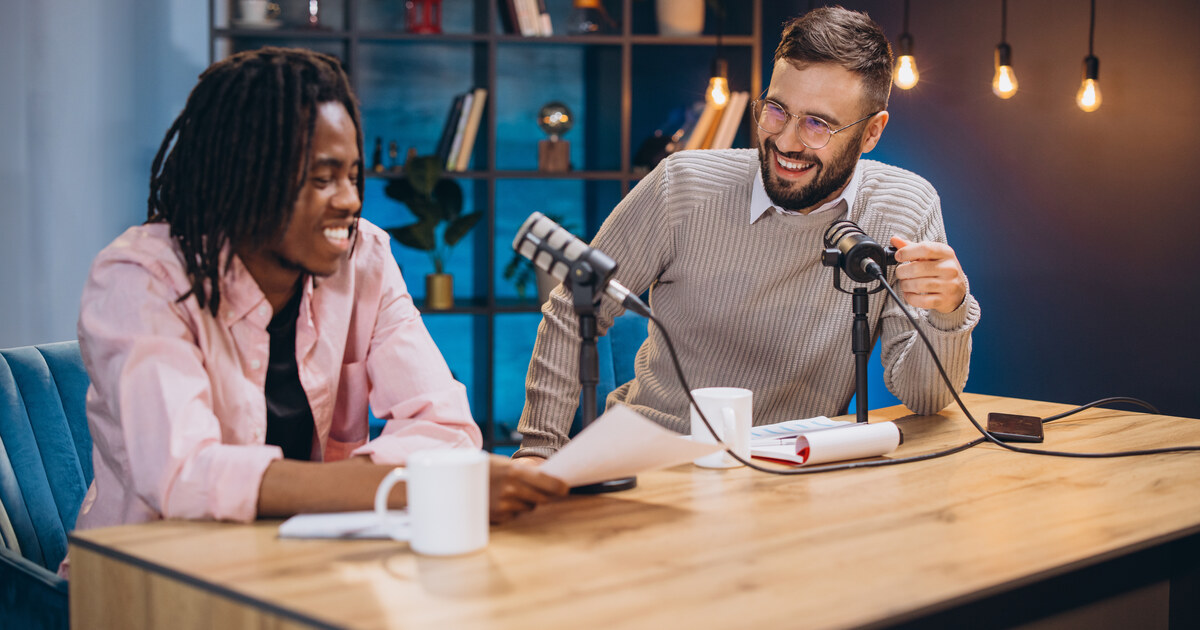 Deux créateurs qui enregistrent un podcast avec des micros sur bras, ambiance chaleureuse