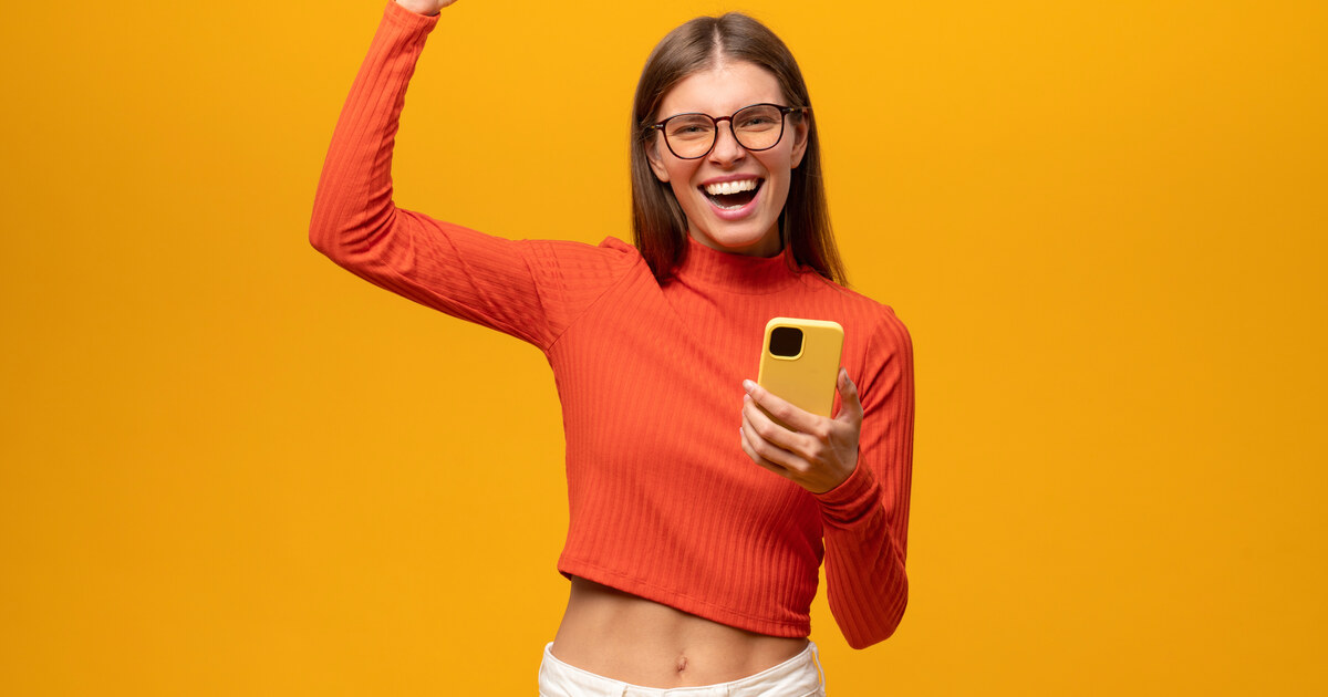 Créatrice qui exulte, téléphone en main, en atteignant un cap d abonnés