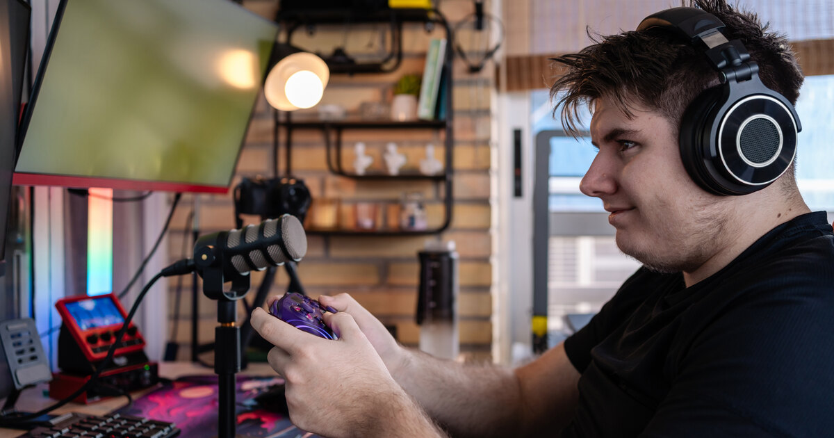 Streamer avec casque à son poste de jeu : micro, écran et manette dans un setup à la maison