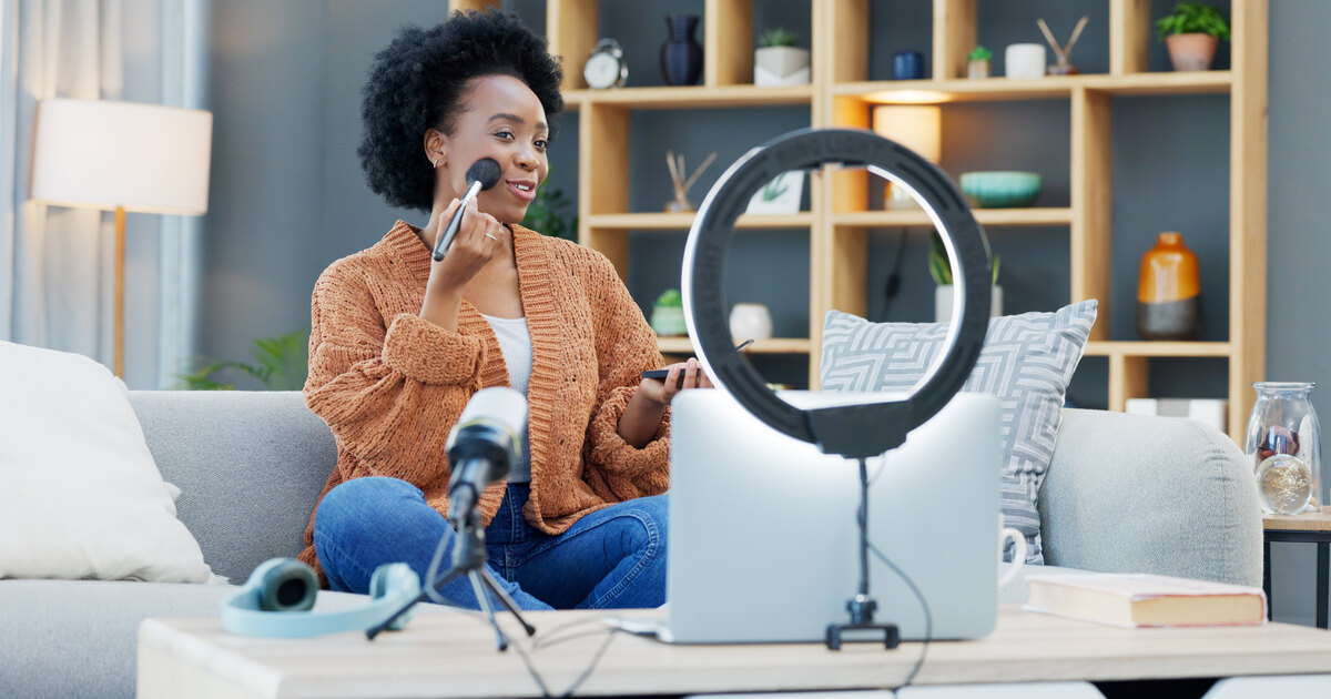 Créatrice noire enregistrant un tutoriel éclairé par une ring light dans un salon chaleureux