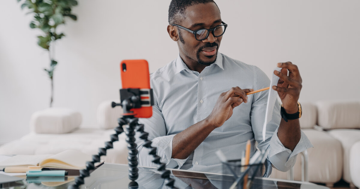 Créateur de contenu filmant une vidéo avec son smartphone sur trépied à son bureau