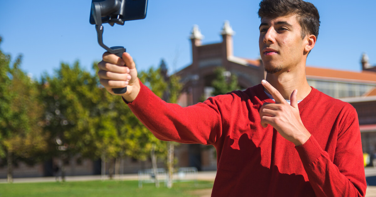 Créateur qui filme avec son smartphone monté sur un stabilisateur gimbal, en extérieur