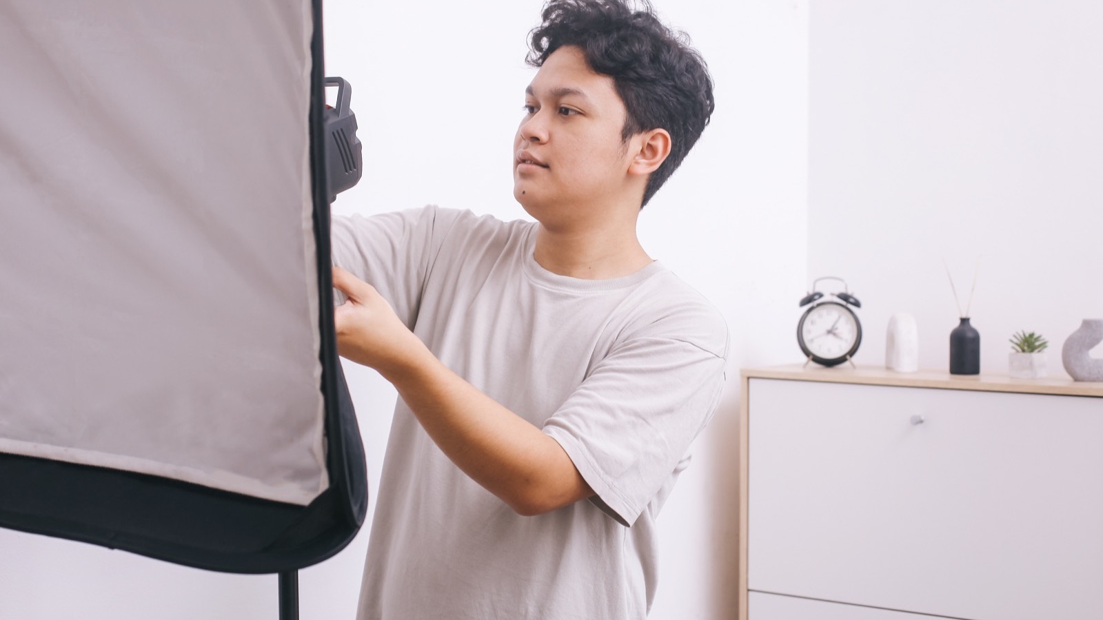 Créateur qui règle sa softbox en montant son studio à la maison