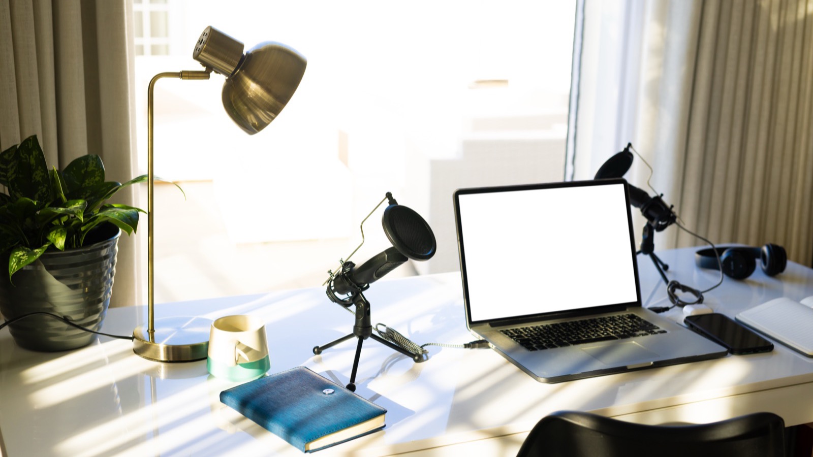 Bureau de créateur en lumière du jour : micro, lampe, ordinateur portable et casque