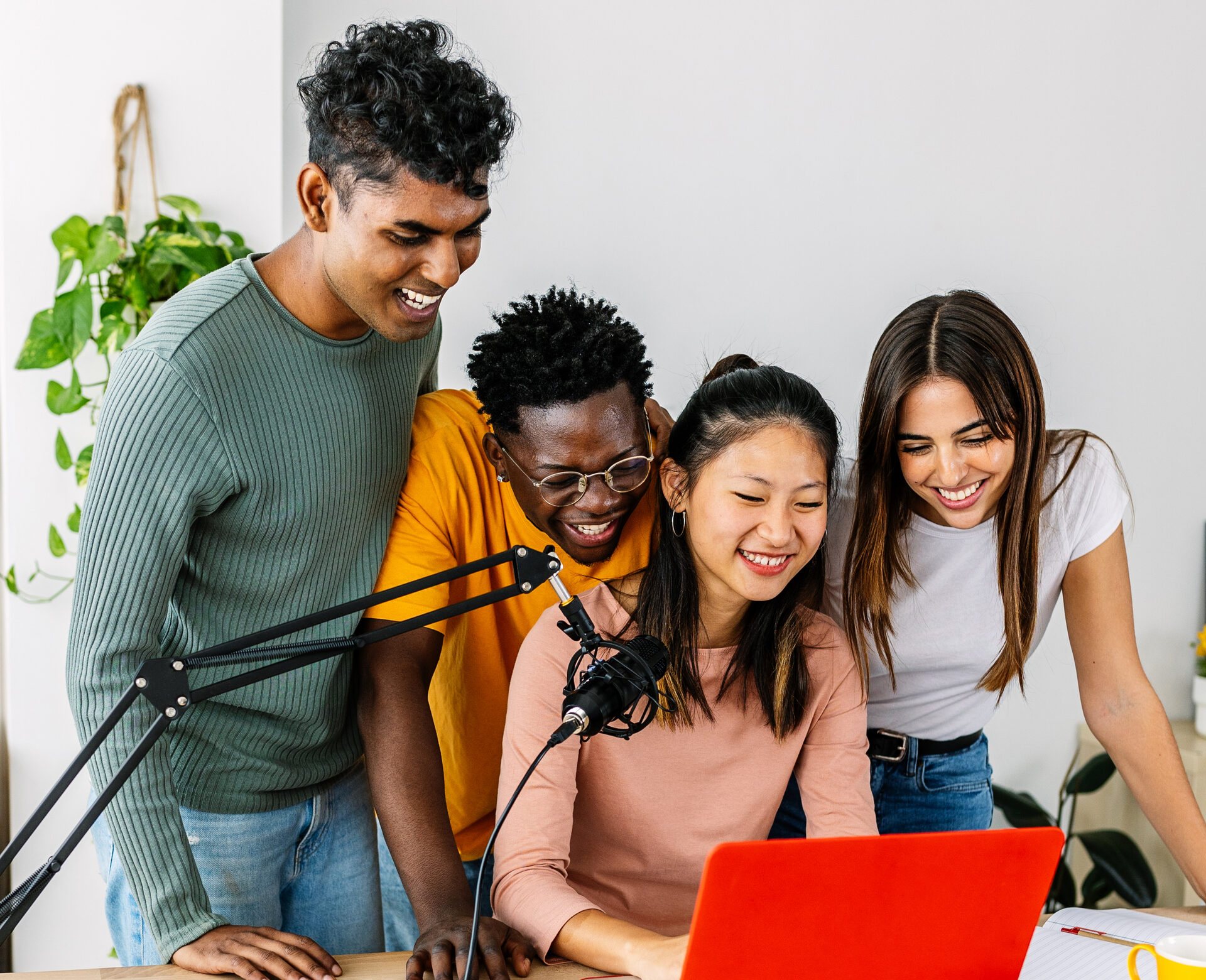 Groupe de créateurs de tous horizons, souriants, autour d'un micro et d'un ordinateur, en train de produire du contenu