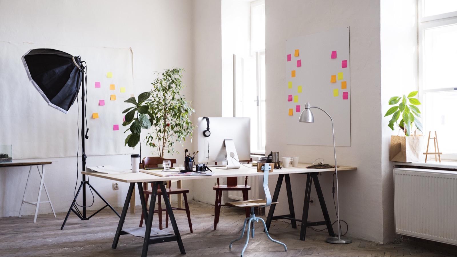 Atelier créatif en lumière du jour : plusieurs postes de travail, éclairage de studio et mur d'idées