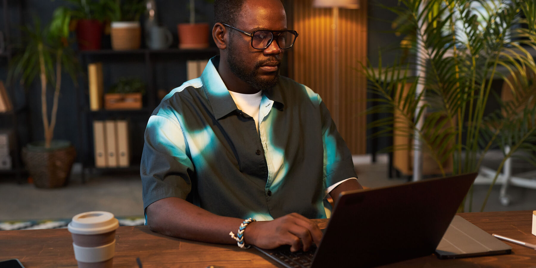 Créateur concentré sur son ordinateur portable, dans un bureau chaleureux