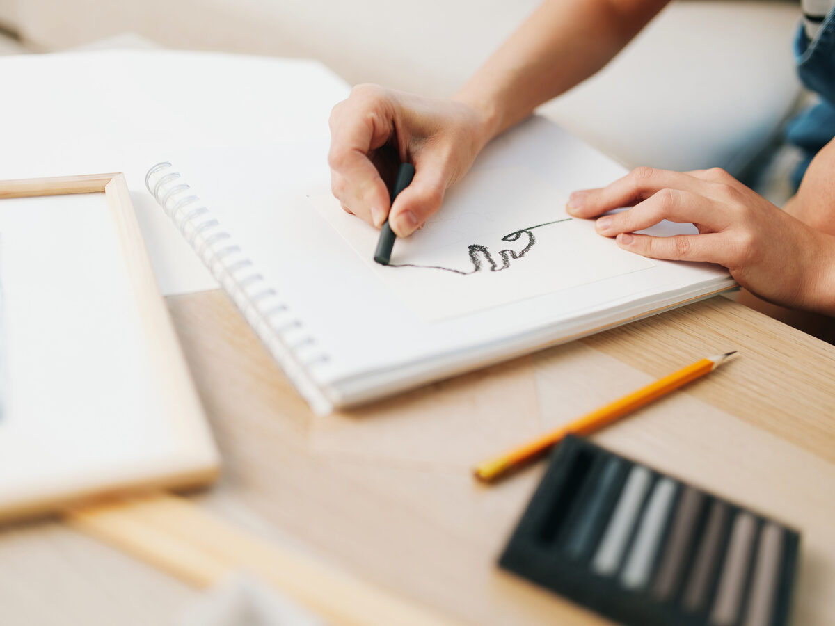 Main qui dessine un logo au feutre dans un carnet de croquis