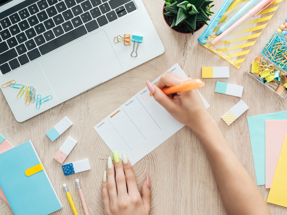 Mains qui remplissent un planning hebdomadaire sur un bureau