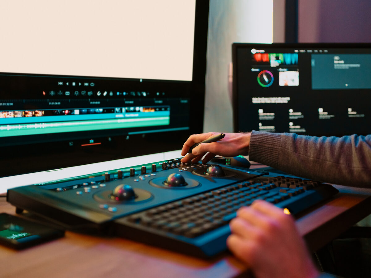 Mains sur une console d'étalonnage devant un écran de montage
