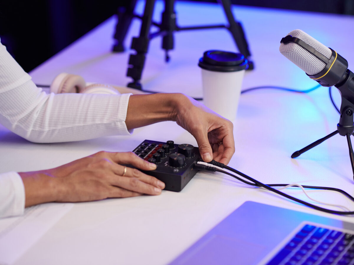 Mains sur une console de streaming, près d'un micro et d'un ordinateur