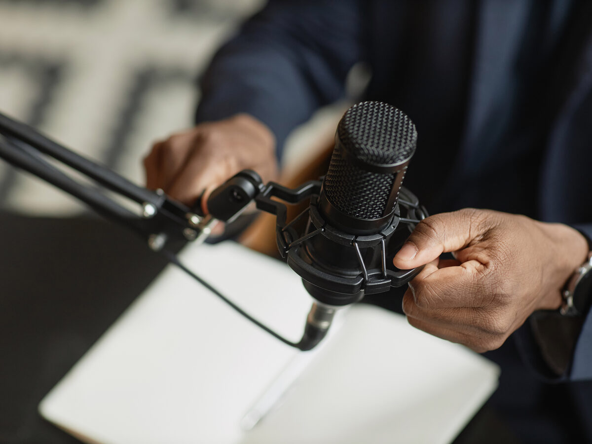Mains qui ajustent un micro de podcast sur son bras articulé