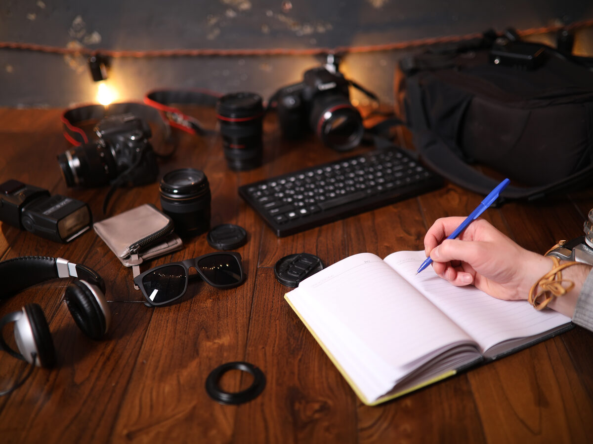 Main qui écrit un script dans un carnet, entourée de matériel vidéo