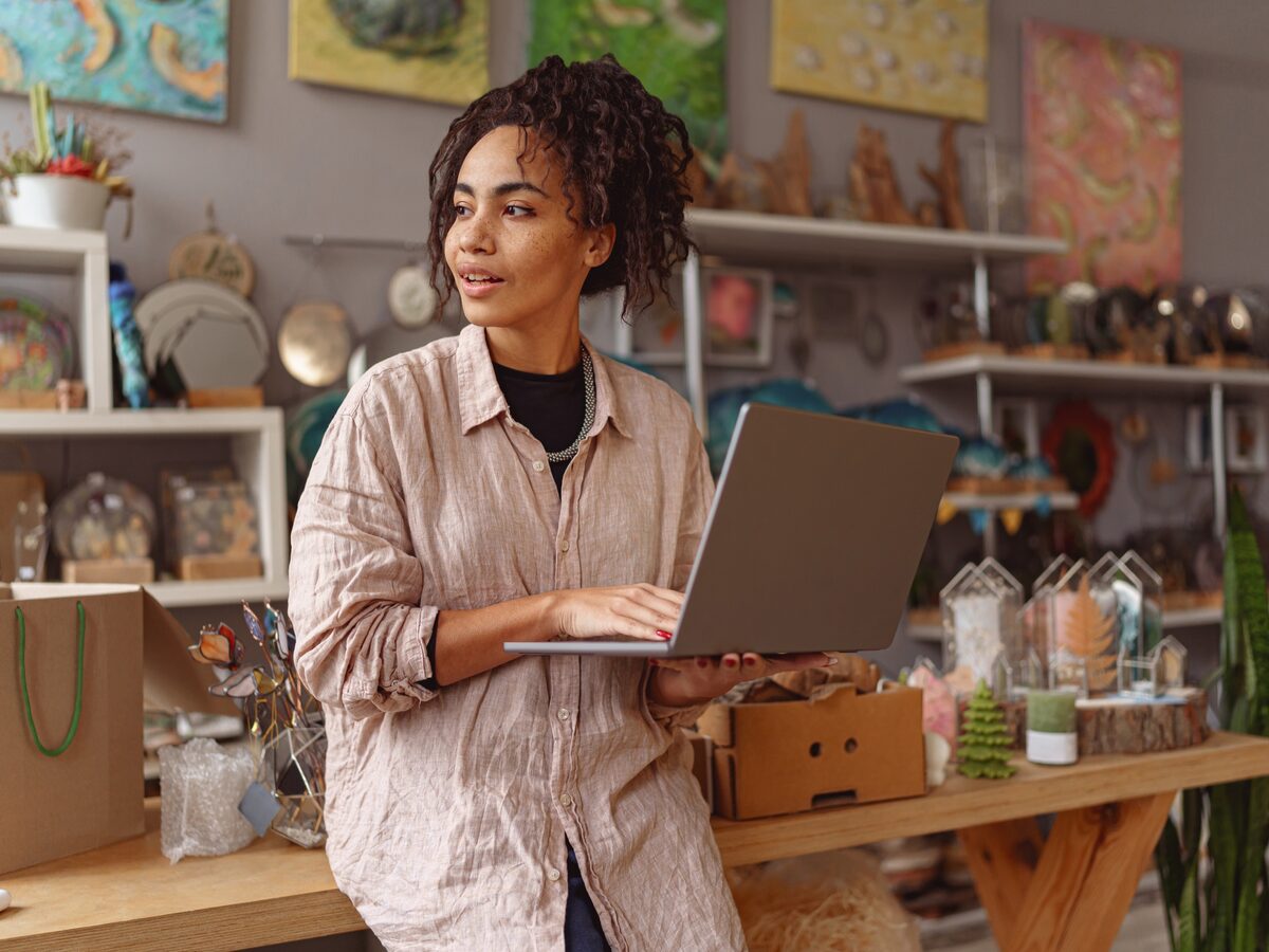 Une commerçante met à jour les informations de sa boutique sur un ordinateur portable