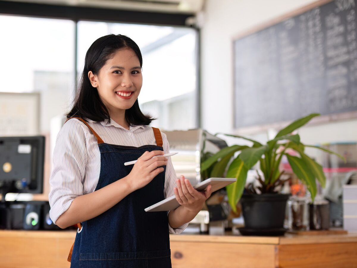 Une gérante de café prend une commande sur sa tablette, derrière son comptoir