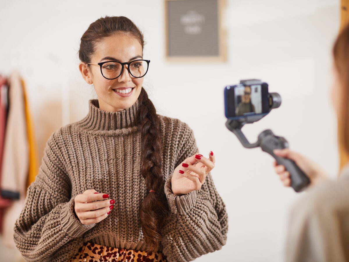 Créatrice filmée au smartphone sur stabilisateur, en format vertical
