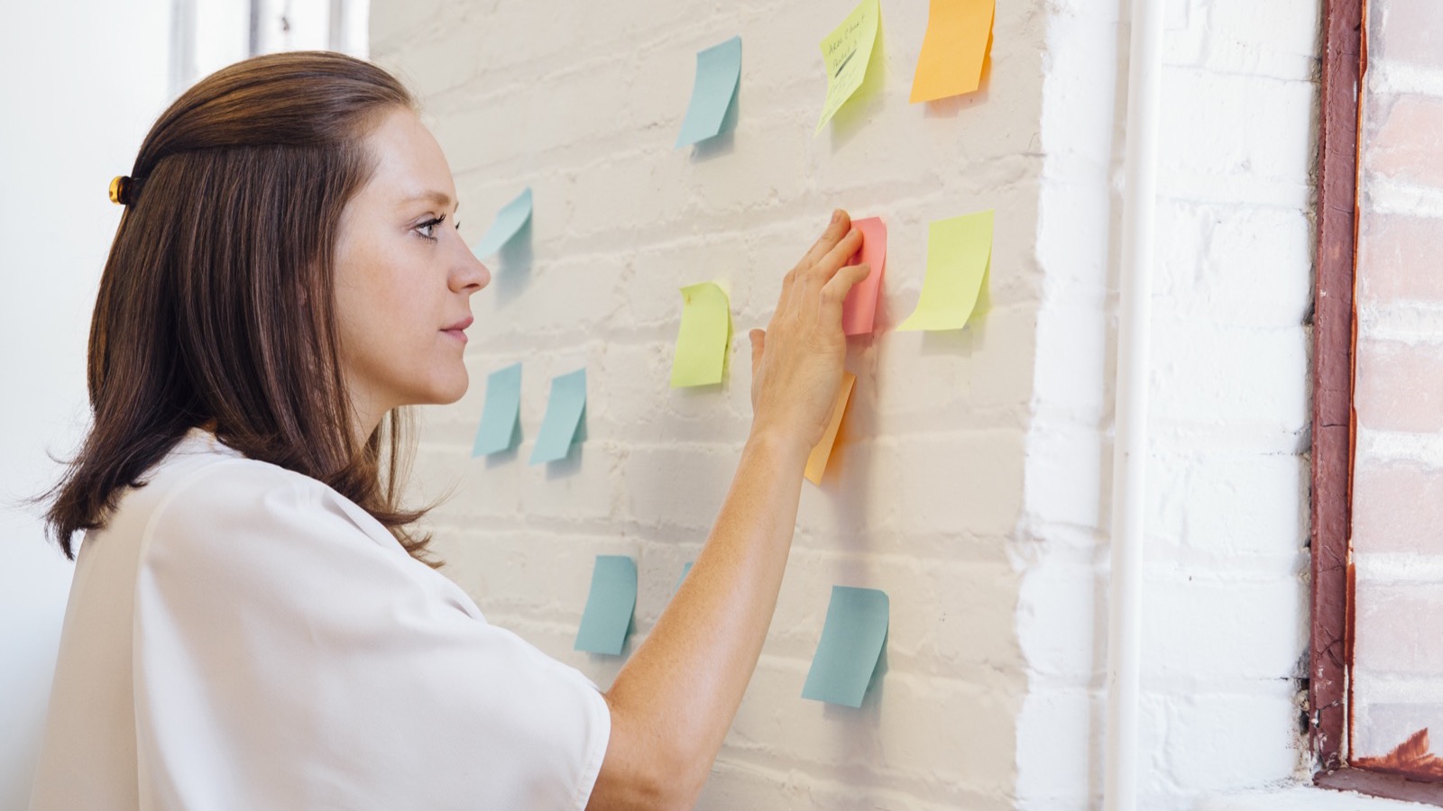 Créatrice qui pose ses objectifs sur un mur de notes autocollantes