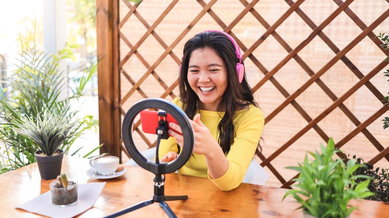 Créatrice en direct sur TikTok, téléphone sur trépied et anneau de lumière, en terrasse