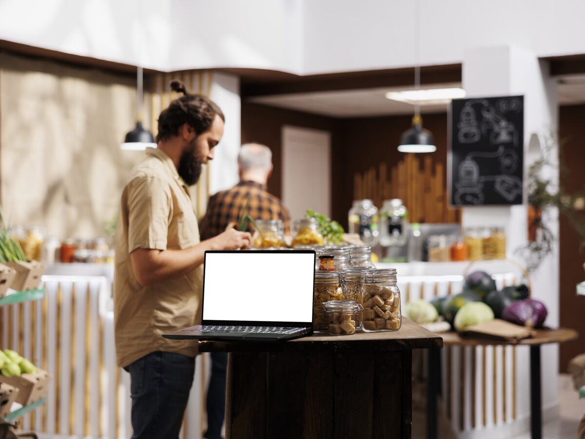 Un épicier consulte son ordinateur portable au milieu de son magasin